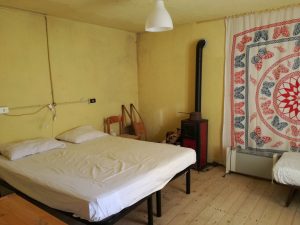 Bedroom at La Casa delle Streghe with a bed, wood-burning stove, and decorative tapestry.
