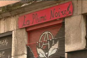 La Plume Noire's storefront with a closed shutter and painted logo on the shutter.