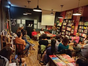 People at a book reading event at Gato Vadio, a bookstore with shelves filled with books.