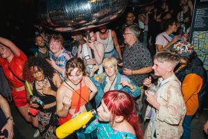 SWARM In The Streets: A lively crowd of diverse people dancing at a party.