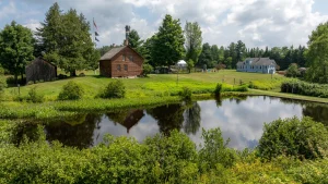 John Brown Farm historic buildings and pond with reflection on a summer day.